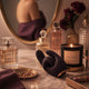 Le rituel beauté — Vanity en marbre blanc, flacons de parfum, bougie figue allumée. Fusion posé parmi les soins, comme un sérum. Le miroir doré reflète une silhouette tranquille.